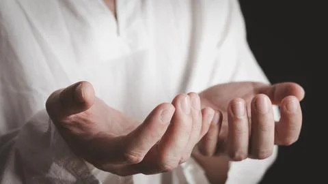 An adult whose hand is prayed on the dark background.Respect for belief in .. Stock Photos