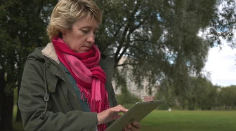 Adult woman using tablet pc in the park Vídeos de archivo 54654126