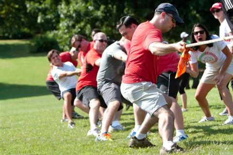 Adults pull rope in team tug-of-war competition Stock Photos