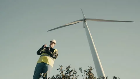 Advancing renewable energy, an engineer uses a tablet to audit wind Stock Footage 233704148