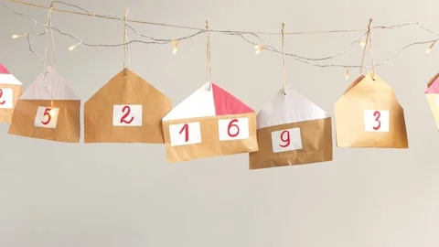 Advent calendar of multi-colored paper houses for gifts hanging on a background Stock Footage 163496581