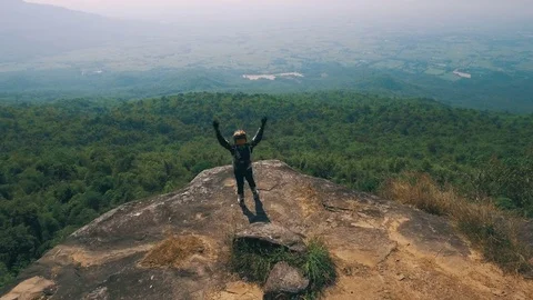 Adventure biker at cliff viewpoint waving his hand cheerfully Stock Footage 82232071