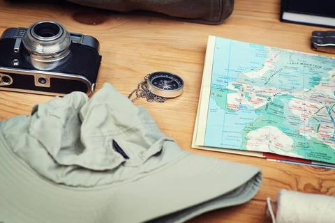 Adventure is out there. a camera, map, compass and a hat on a wooden table. Stock Photos