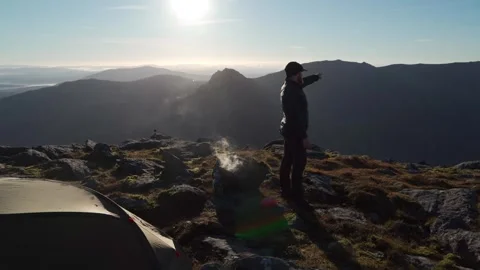 An adventurer pointing into the mountains while cooking something Vidéo 253788767