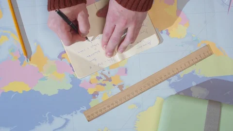 Adventurer writes in a notebook on a table with a map Stock Footage 129977005