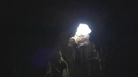 Adventurers crawling down a long ladder and entering a rocky mine Stock Footage 79796598