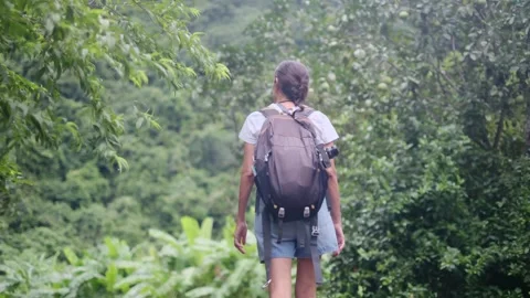 Adventurous backpacker as she embarks on a journey through lush jungles Stock Footage 252035975