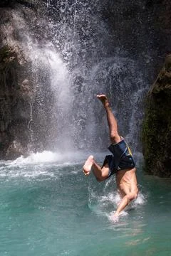 Adventurous dive into a turquoise natural pool beside a waterfall. Stock Photos