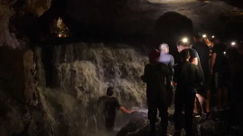Adventurous explorers discovering a waterfall inside the Jumandy caves 스톡 동영상 334934314