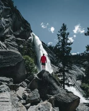 An adventurous guy standing in front of a huge waterfall in the Yosemite Vall Stock Photos