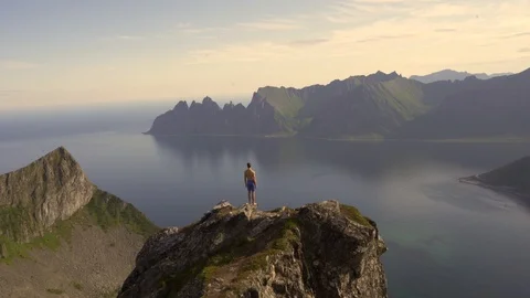 Adventurous man is standing on top of the mountain and enjoying the beautiful vi Stock Footage 126898241