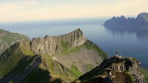 Adventurous man is standing on top of the mountain and enjoying the beautiful vi Stock Footage 126898462