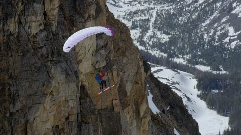 Adventurous paraskier doing flip while flying from the snowy mountain cliff Stock Footage 116743470
