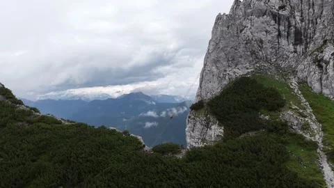 Adventurous person base jumping from a high alpine cliff Stock Footage 319283621
