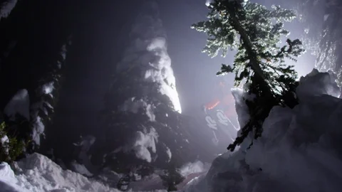 Adventurous skier jumping down the snowy mountain at night Stock Footage 116738067