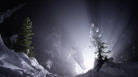 Adventurous skier jumping down the snowy mountain at night Stock Footage 116738160