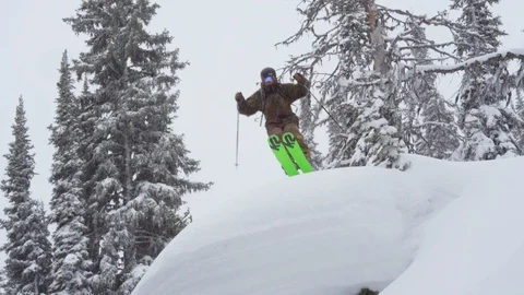 Adventurous skier jumping down the snowy mountain slope Stock Footage 116738691
