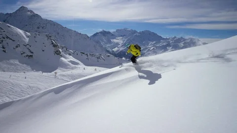 Adventurous skier making turns while skiing down from ridge of snowy mountain Stock Footage 116740270