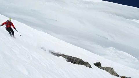 Adventurous skier making turns while skiing down the snowy mountain slope Stock Footage 116744313