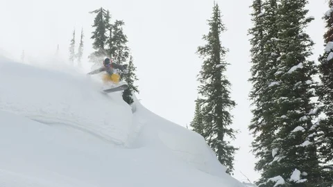 Adventurous snowboarder performing Indy grab trick on snowy mountain slope Stock Footage 116788679