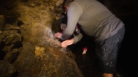 Adventurous spelunkers exploring a dark wet cave Vídeos de archivo 334934754
