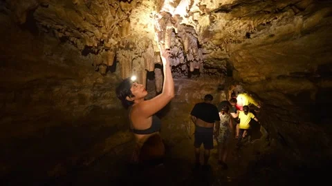 Adventurous tourists exploring underground caverns with headlamps Vídeos de archivo 334934632