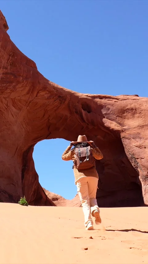 Adventurous woman exploring monument valley natural arch Stock Footage 334852758