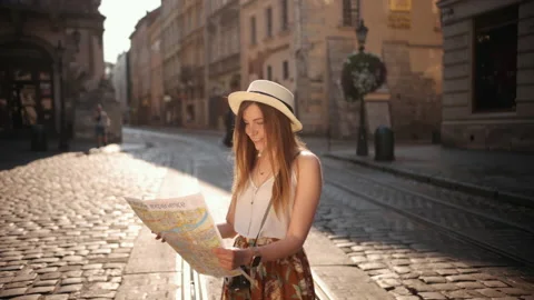 Adventurous woman navigating in with topographic map by city. Cheerful girl Stock Footage 157586720
