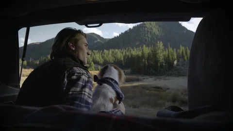 Adventurous Young Man Sits In Back Of SUV With Dog, Pets Her, Looks Out At View Stock Footage