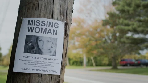 An advertisement for a missing young woman hangs on a pole near the road Stock Footage 165950965