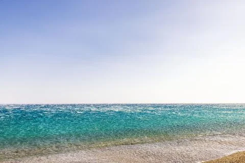 Aegean sea waves returning from pebble beach during strong offshore wind. Stock Photos