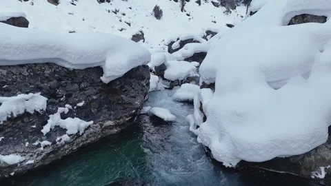 Aerail pull back through snow covered rocks revealing icicles and ponds Video stock 328961045