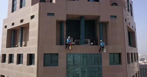 Aereal shot of professional window washers in  a building in Tel Aviv Stock Footage 145390380