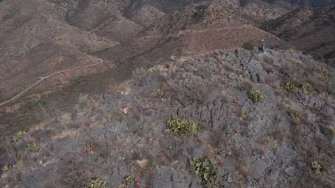 Aerial of 2 men on the summit of a rugged peak in Arizona Stock Footage 259737944