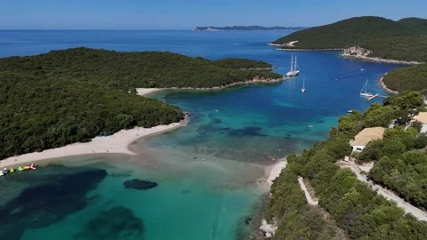 Aerial 4K horizontal view of Bella Vraka bay with anchored yachts and green isla Stock Footage 340566829