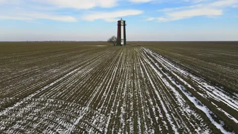 Aerial 4k - lighthouse on the field with green grass and blue sky, snowy winter Stock Footage 220730033
