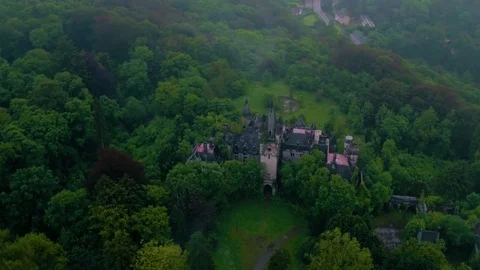 Aerial of abandoned castle surrounded with dense lush green trees Stock Footage 81528680