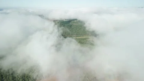 Aerial above the clouds over beautiful green fields and a river. Low clouds. Stock Footage 233217998