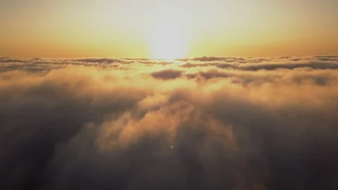 Aerial from above clouds in warm orange morning or evening sun light. Cloudscape Stock Footage 117444411