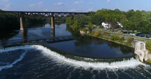 Aerial Above Nice River Valley And Water Flows Over Shaped Dam By Train Trestle Stock Footage 200848882