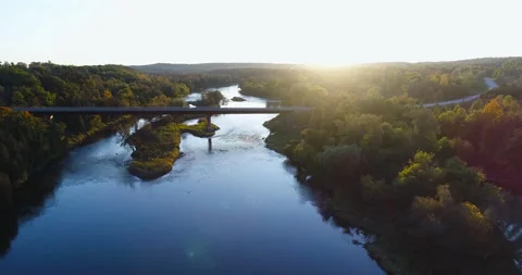 Aerial Above River Sunset Light Moving Toward Bridge Among Dark Forest Landscape Stock Footage 200015944