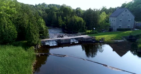 Aerial Above Small River Over Dam Beside Stone House In Forest Valley At Dust Vidéo 237602830