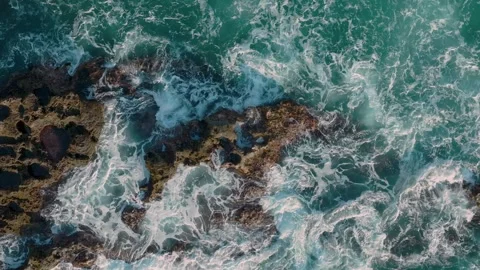 Aerial: Abstract texture of rough ocean surf crashing over rocks in slow motion. Stock Footage 263262176