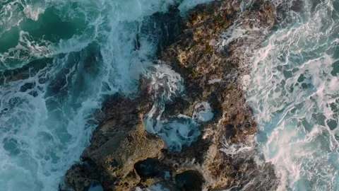 Aerial: Abstract texture of rough ocean surf crashing over rocks in slow motion. Stock Footage 263264076