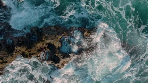 Aerial: Abstract texture of rough ocean surf crashing over rocks in slow motion. Stock Footage 263265102