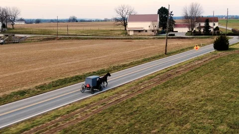 Aerial Amish horse and buggy trots down the road toward a stop sign, Stock Footage