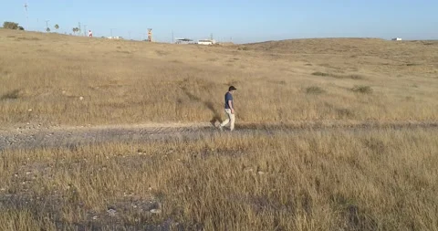 Aerial and side view of young man walking on the outskirts of the city Stock Footage 133537215