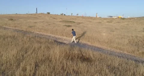 Aerial and side view of young man walking on the outskirts of the city Stock Footage 133620035