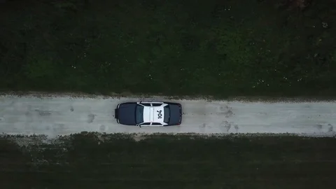 AERIAL: angled down track of a police car traveling through a dirt road Stock Footage 100244680