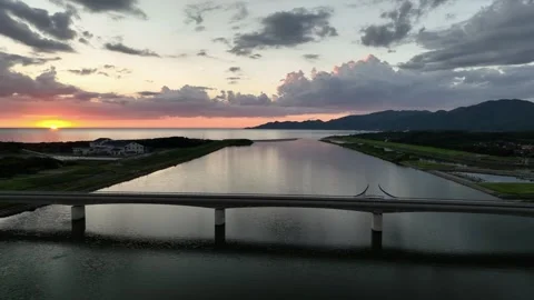 Aerial approach to empty bridge over coastal river with dramatic sunset Stock Footage 248306916